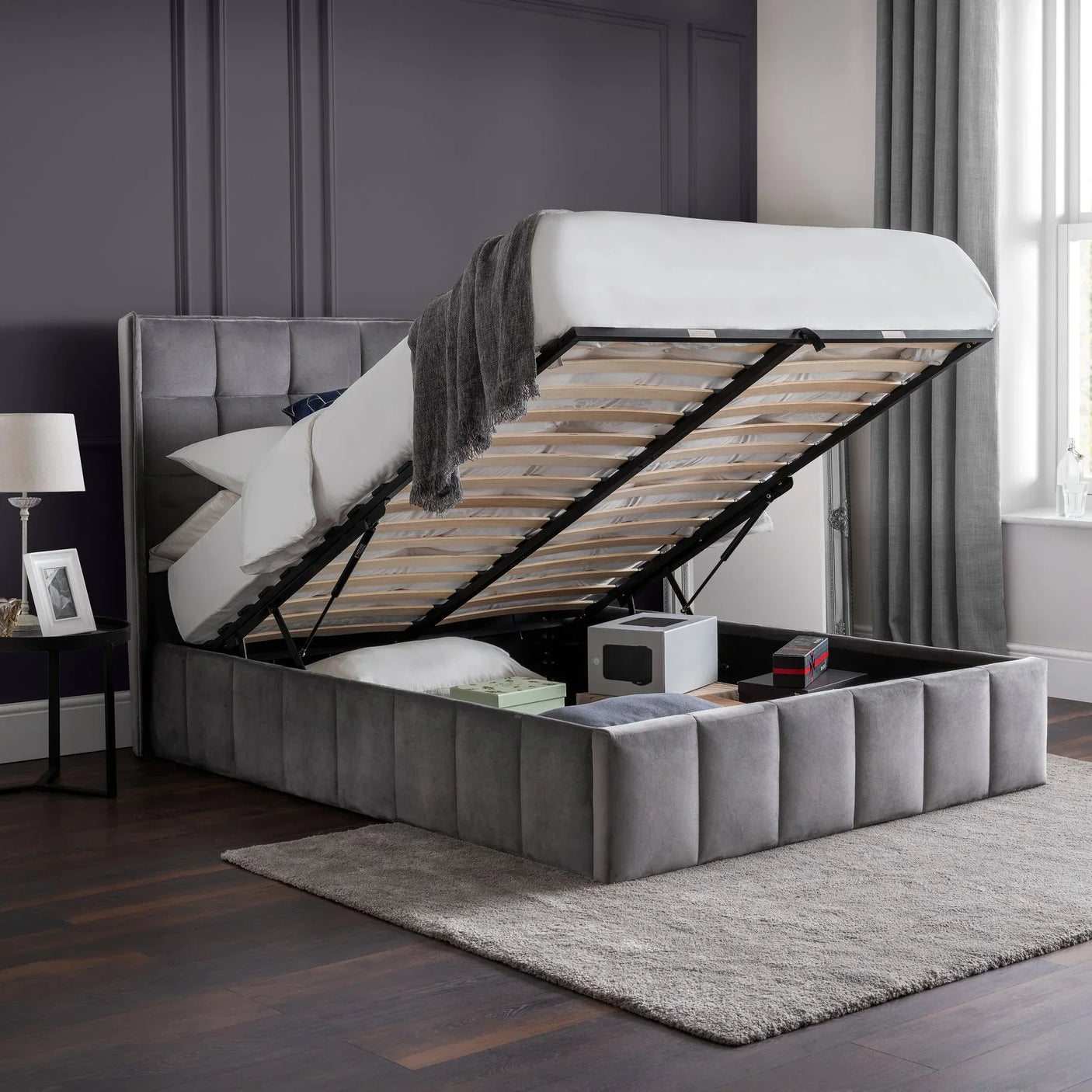 Grey ottoman storage bed with open lift-up base, upholstered headboard, and bedroom decor