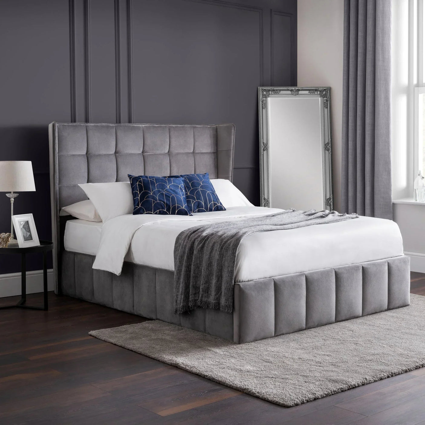 Grey upholstered ottoman bed with tall headboard in modern bedroom setting