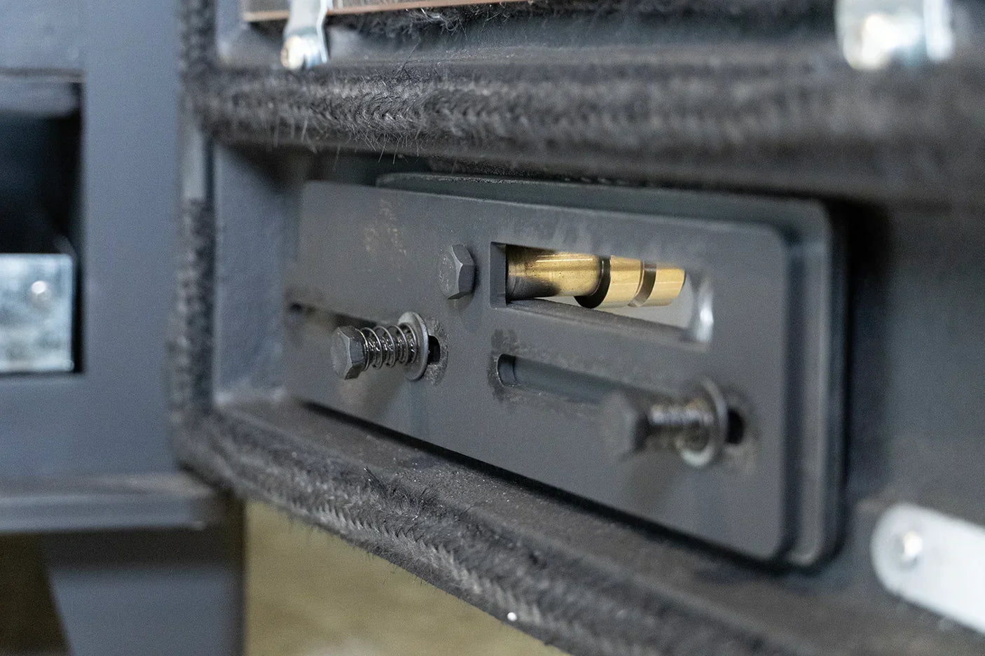 Close up of stove door mechanism showing internal metal latch and adjustment bolts