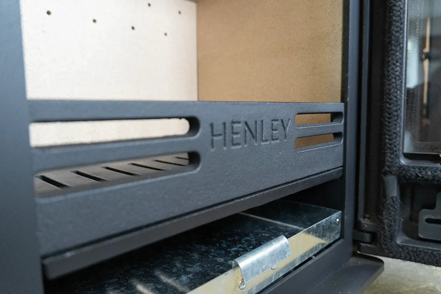 Cast iron stove interior with Henley branding and removable ash pan drawer