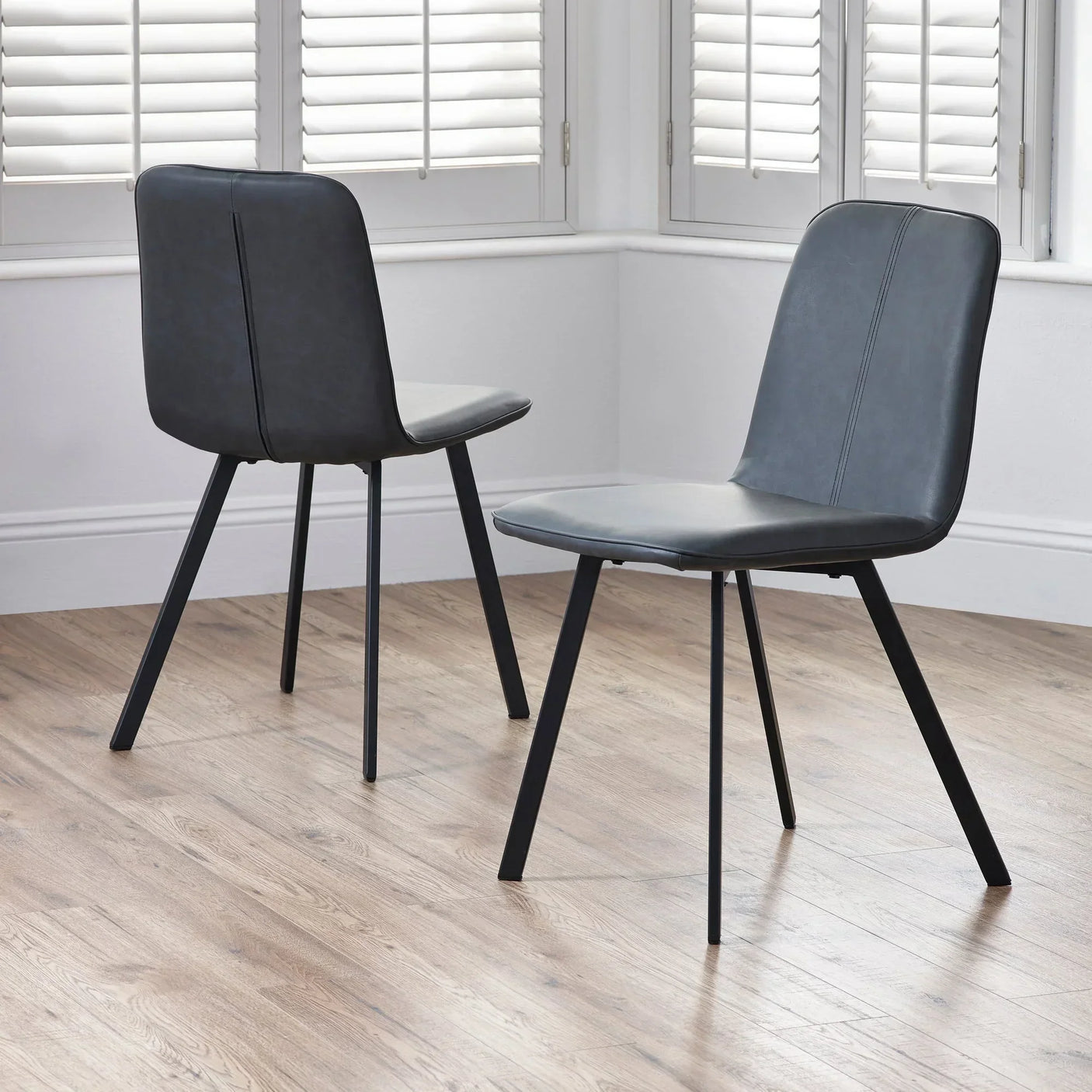 black dining chairs with metal legs in modern room with wood flooring and white shutters