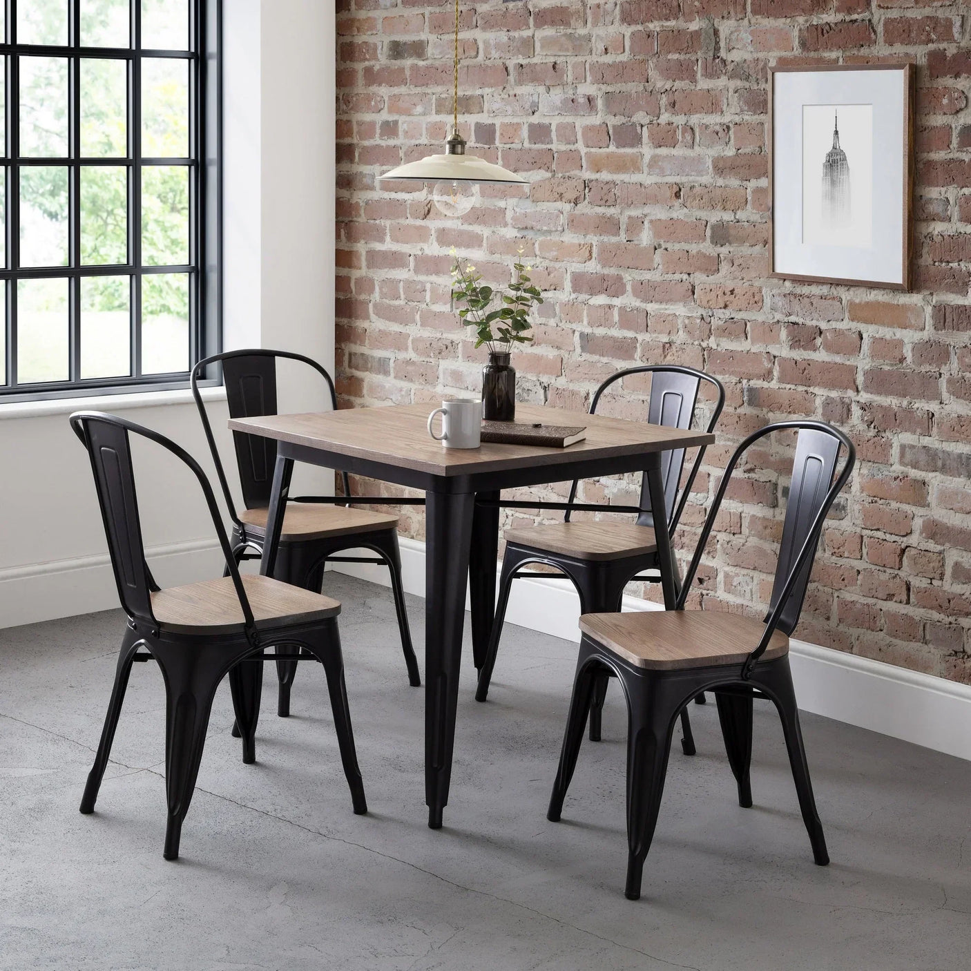 Industrial square dining table with four black metal chairs, wood seats, brick wall backdrop