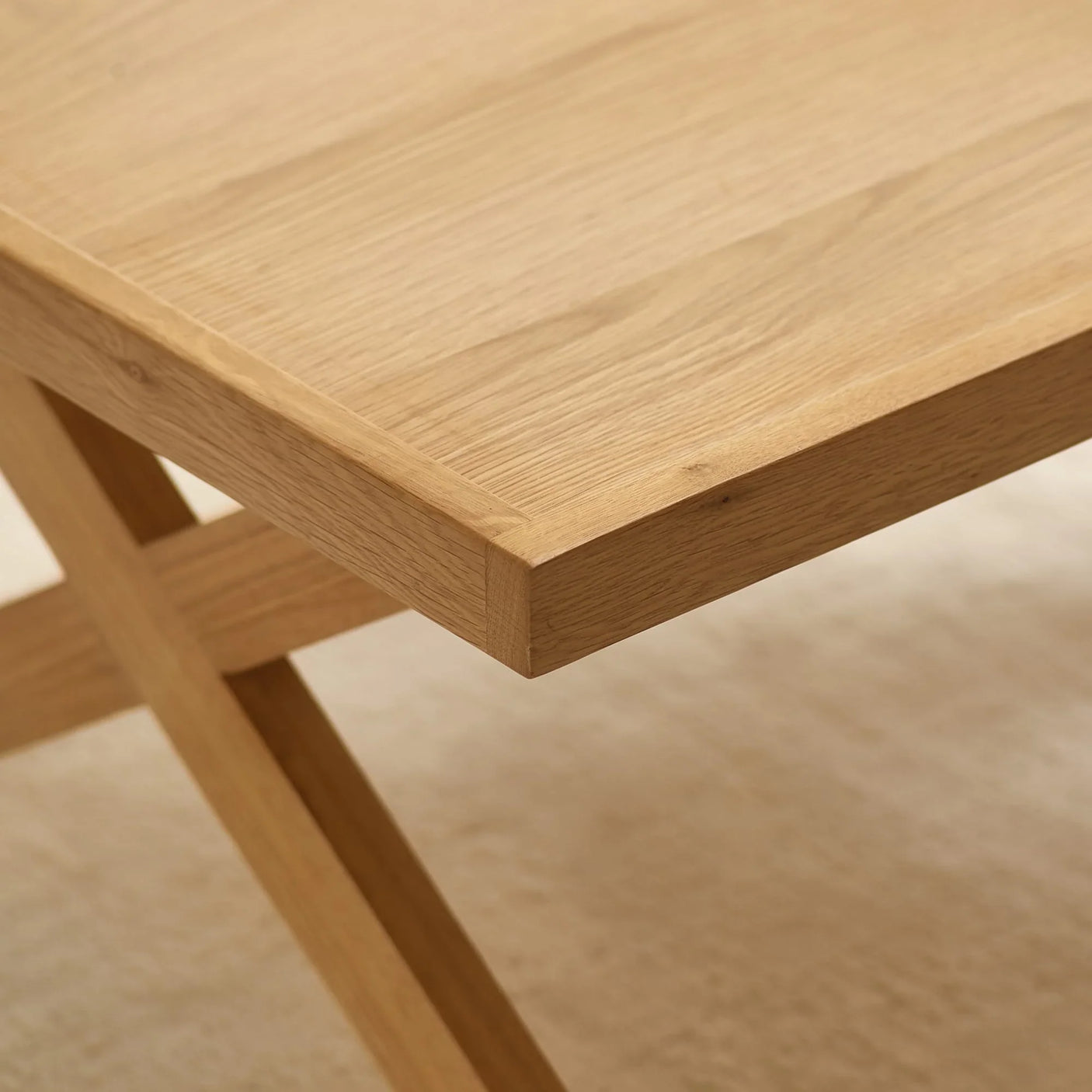 Oak dining table corner with smooth wood grain and chamfered edge on neutral background