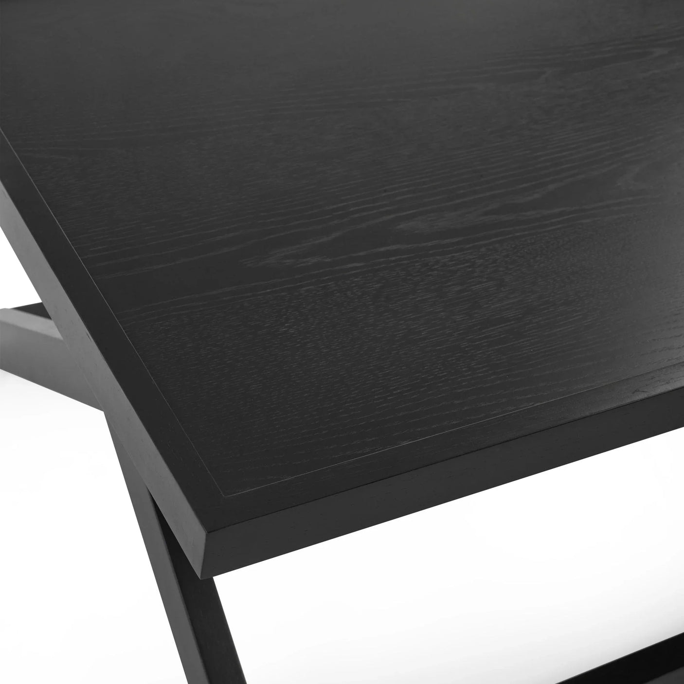 Close-up of black wood dining table corner with visible grain and angled leg