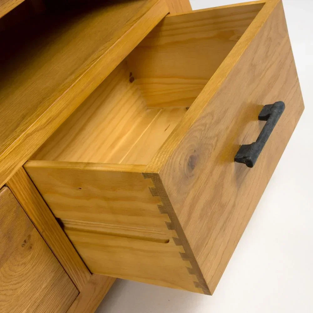 Solid wood drawer unit with black metal handle, close-up of open drawer and dovetail joints