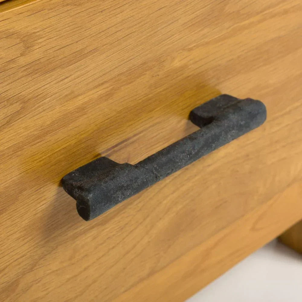 Close-up of black metal drawer handle on oak wood furniture