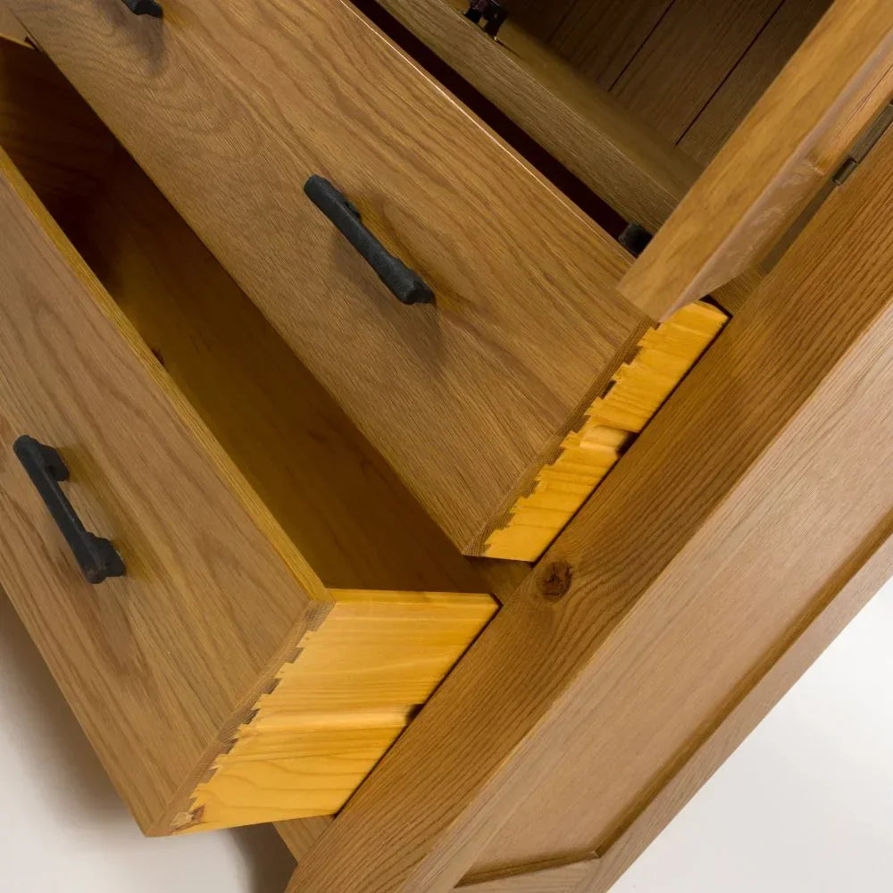Oak chest of drawers with black handles and dovetail joints, close up view