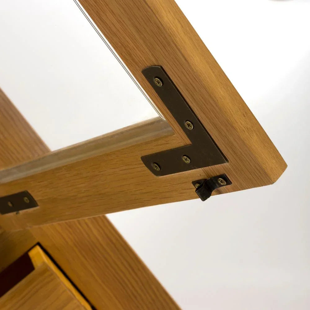 Oak dining table corner detail with visible black metal hinge and wood grain finish