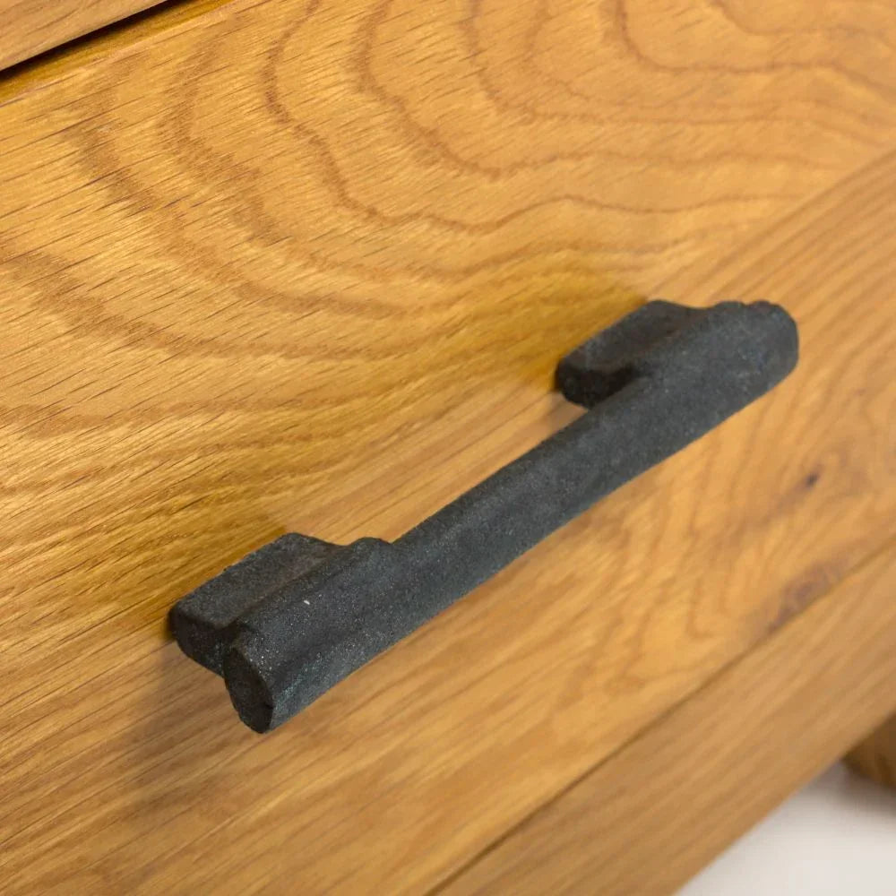 Black metal drawer handle on natural oak wood chest