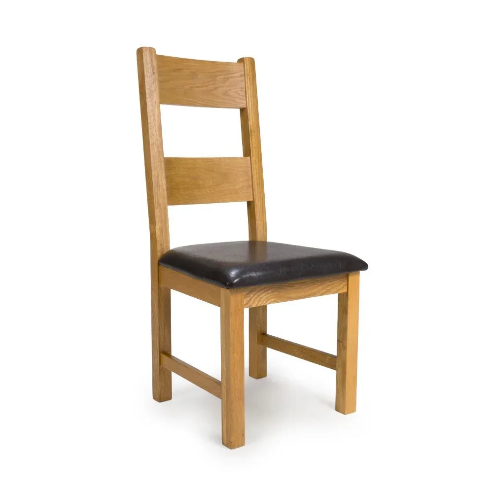 Oak dining chair with dark faux leather seat and slatted back on white background