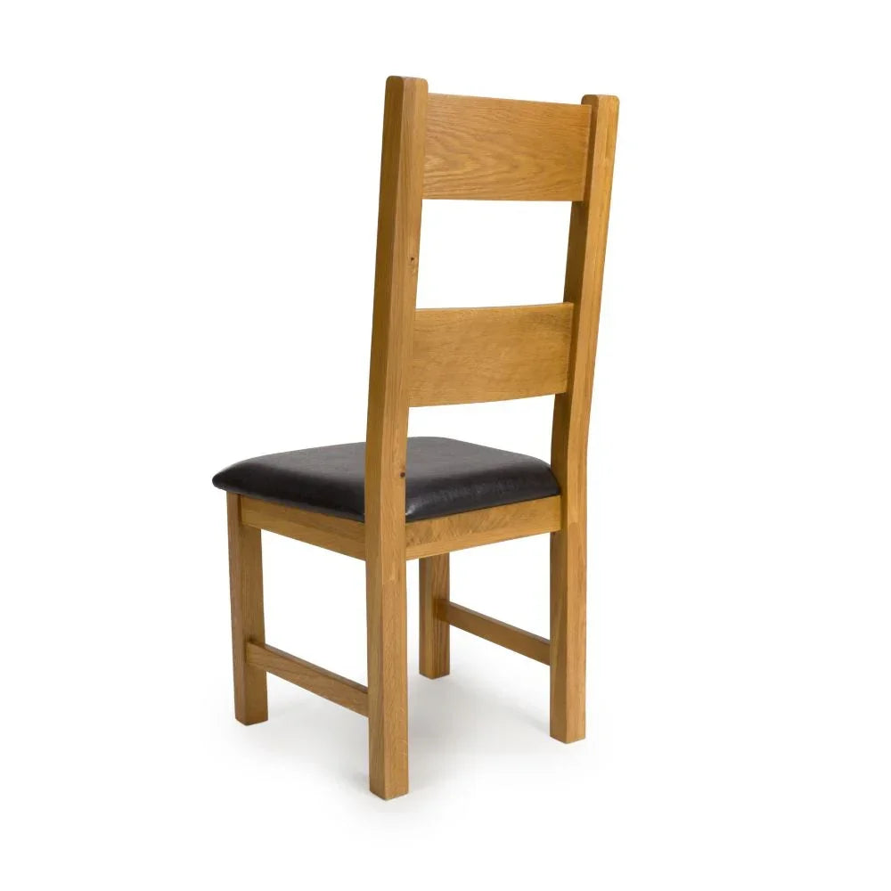 Solid oak dining chair with slatted back and black cushioned seat, rear angled view
