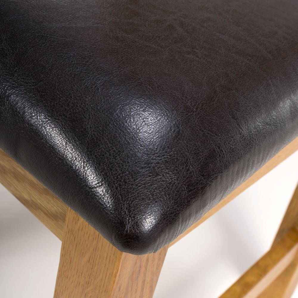 Close-up of black leather stool seat with oak wooden legs