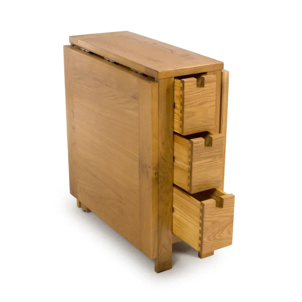 Oak drop leaf dining table with three side drawers, shown at an angle