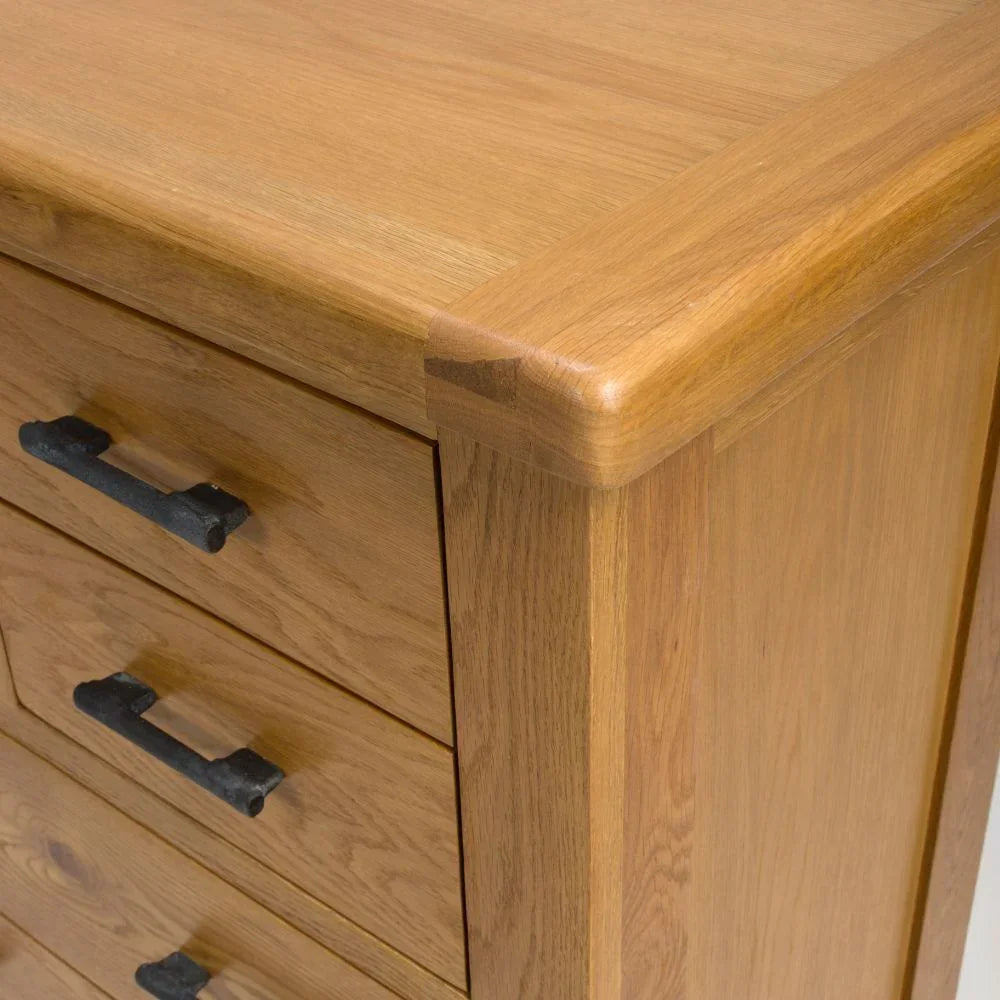 Oak chest of drawers with black metal handles and smooth rounded corner detail