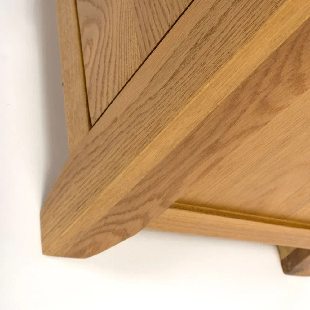 Close-up of oak table corner showing wood grain and angled leg joints