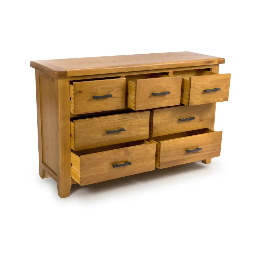 Oak chest of drawers with seven open drawers and black metal handles on white background