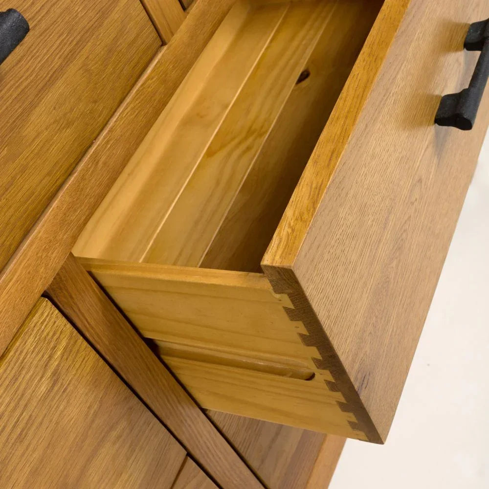 Oak chest of drawers with open drawer showing dovetail joints and black metal handle