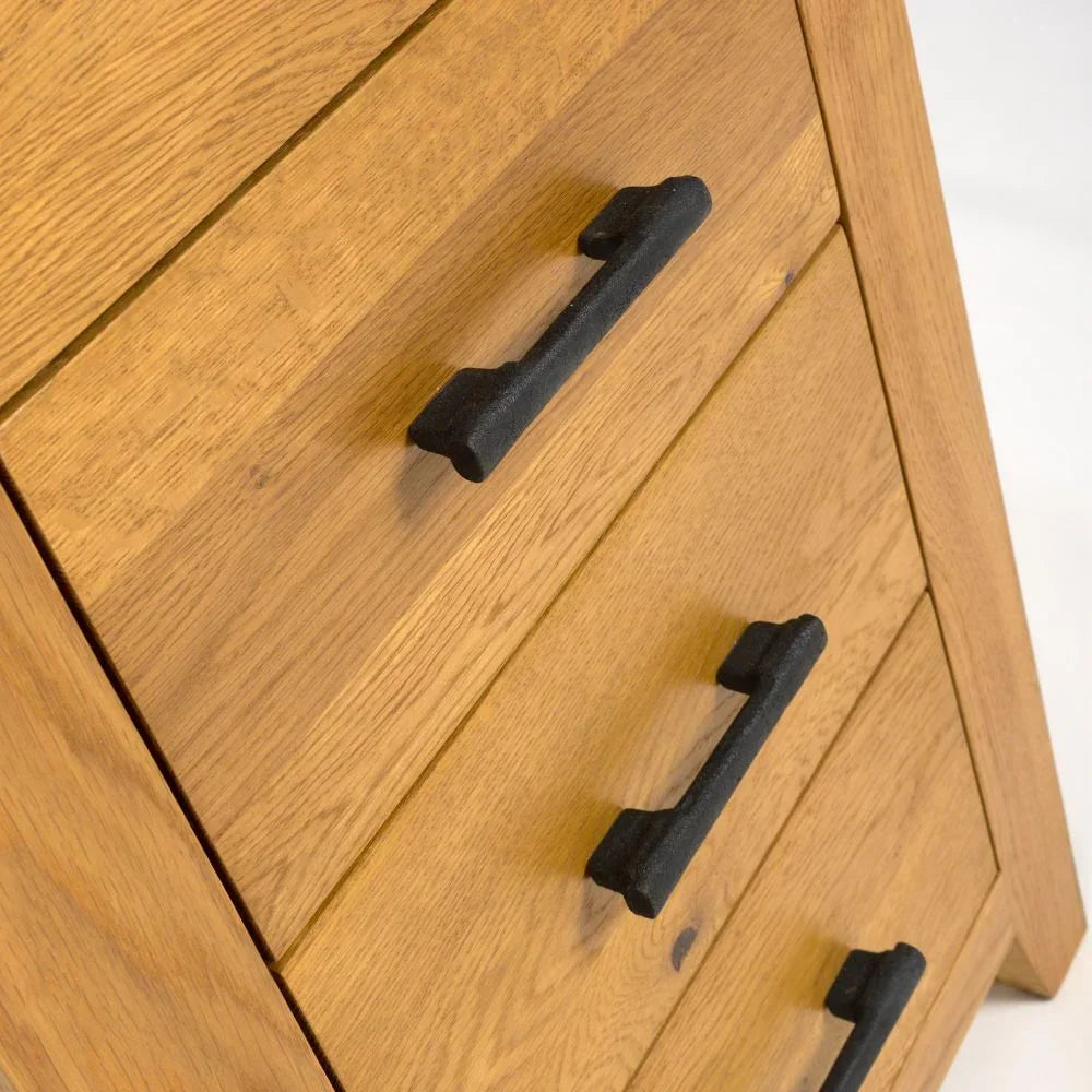 Oak chest of drawers with black metal handles, close-up view of drawer fronts
