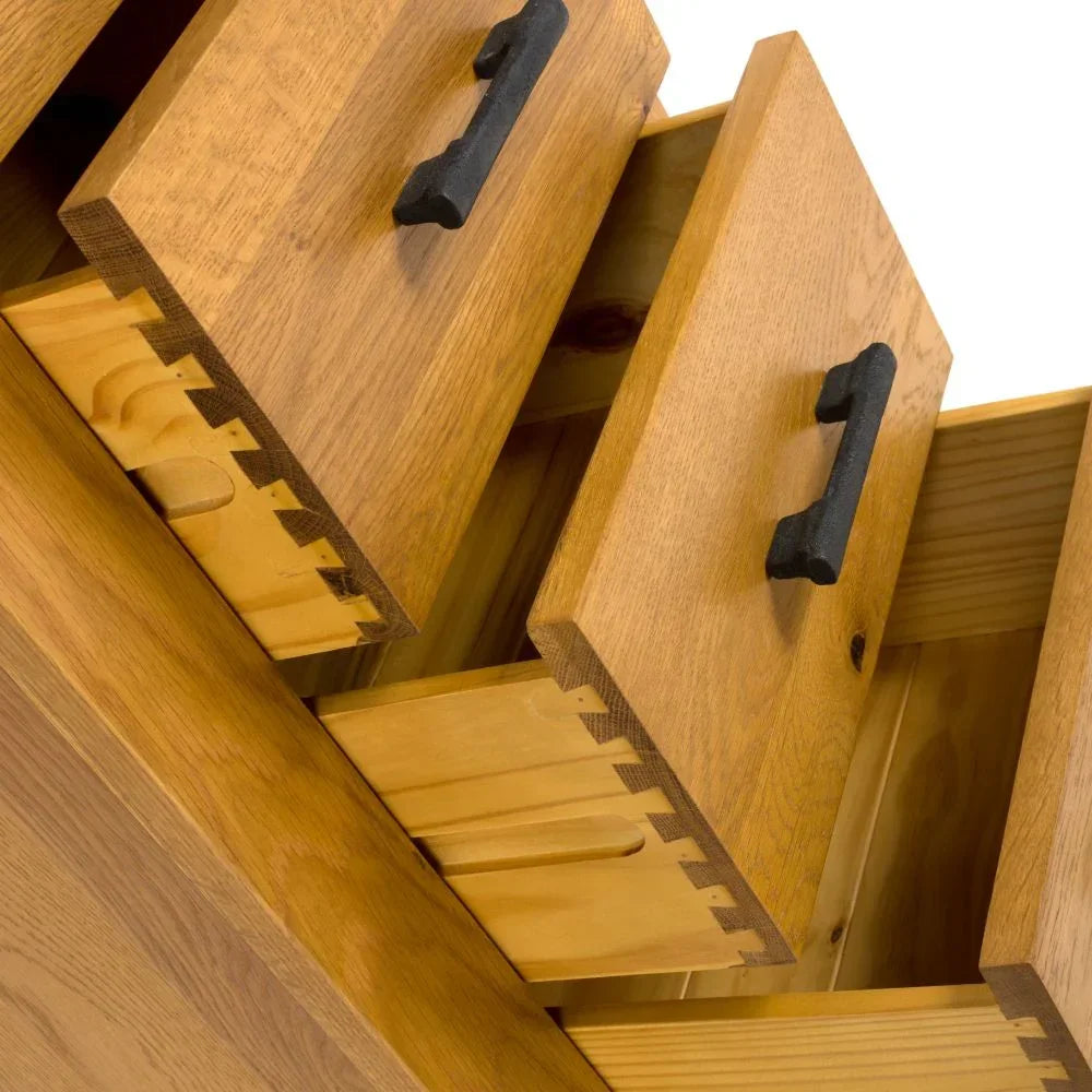 Oak chest of drawers with black metal handles and dovetail joints, close-up
