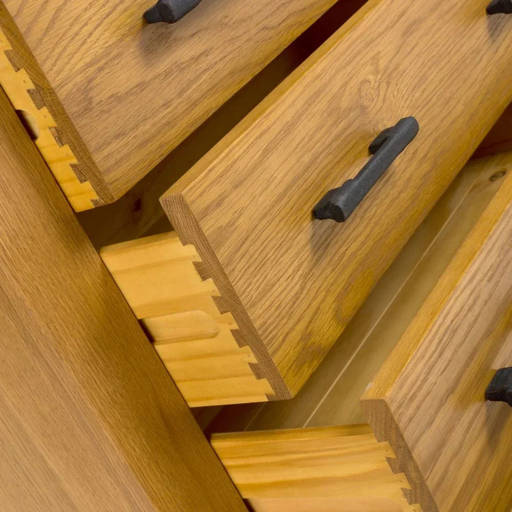 Oak chest of drawers with dovetail joints and black metal handles closeup