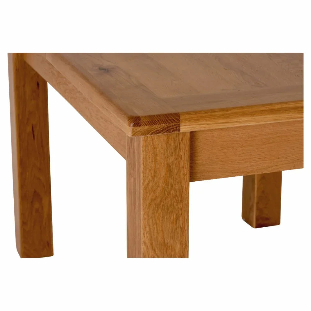 Close up of solid oak dining table corner with natural wood grain and square leg design