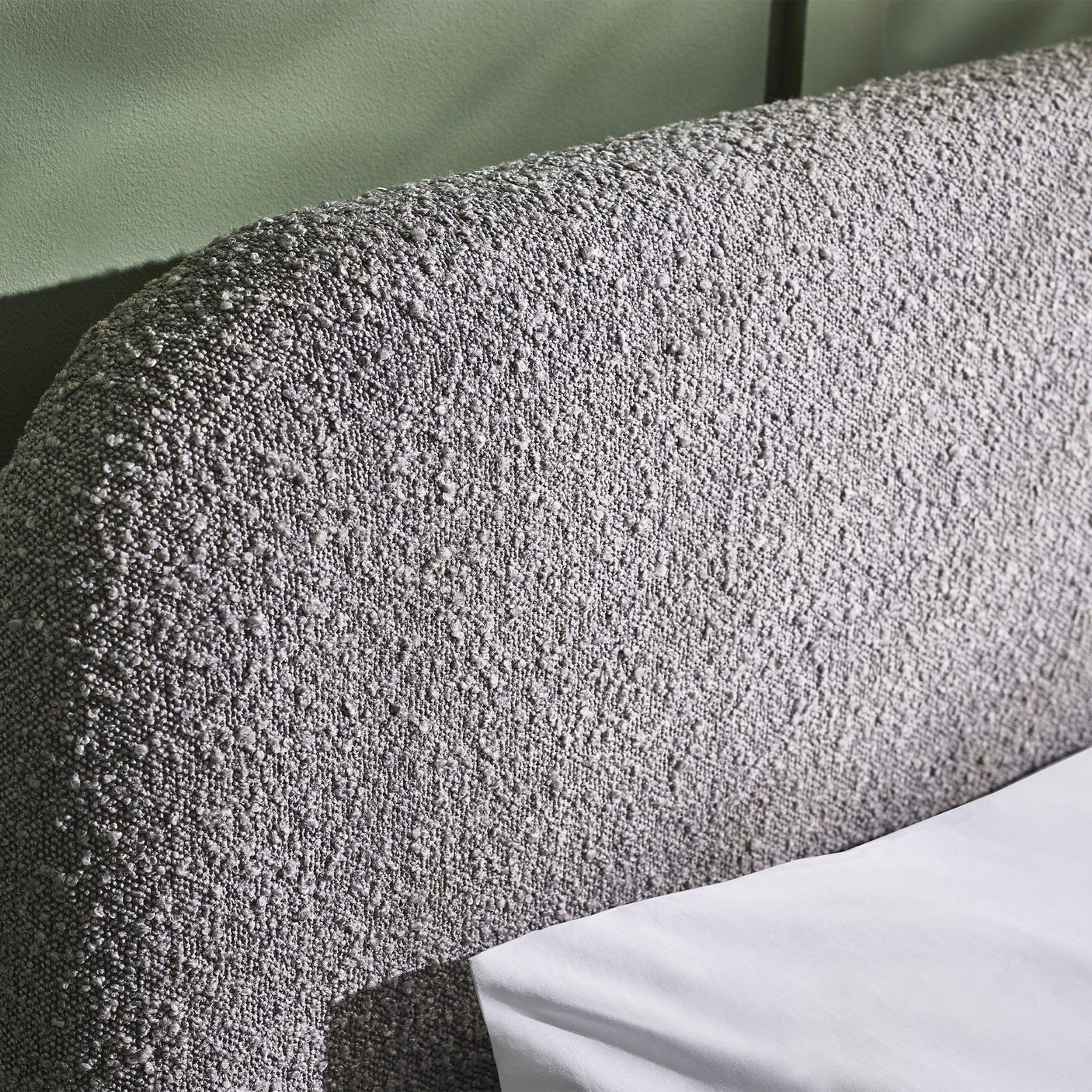 Closeup of textured grey upholstered bed headboard with soft fabric detail