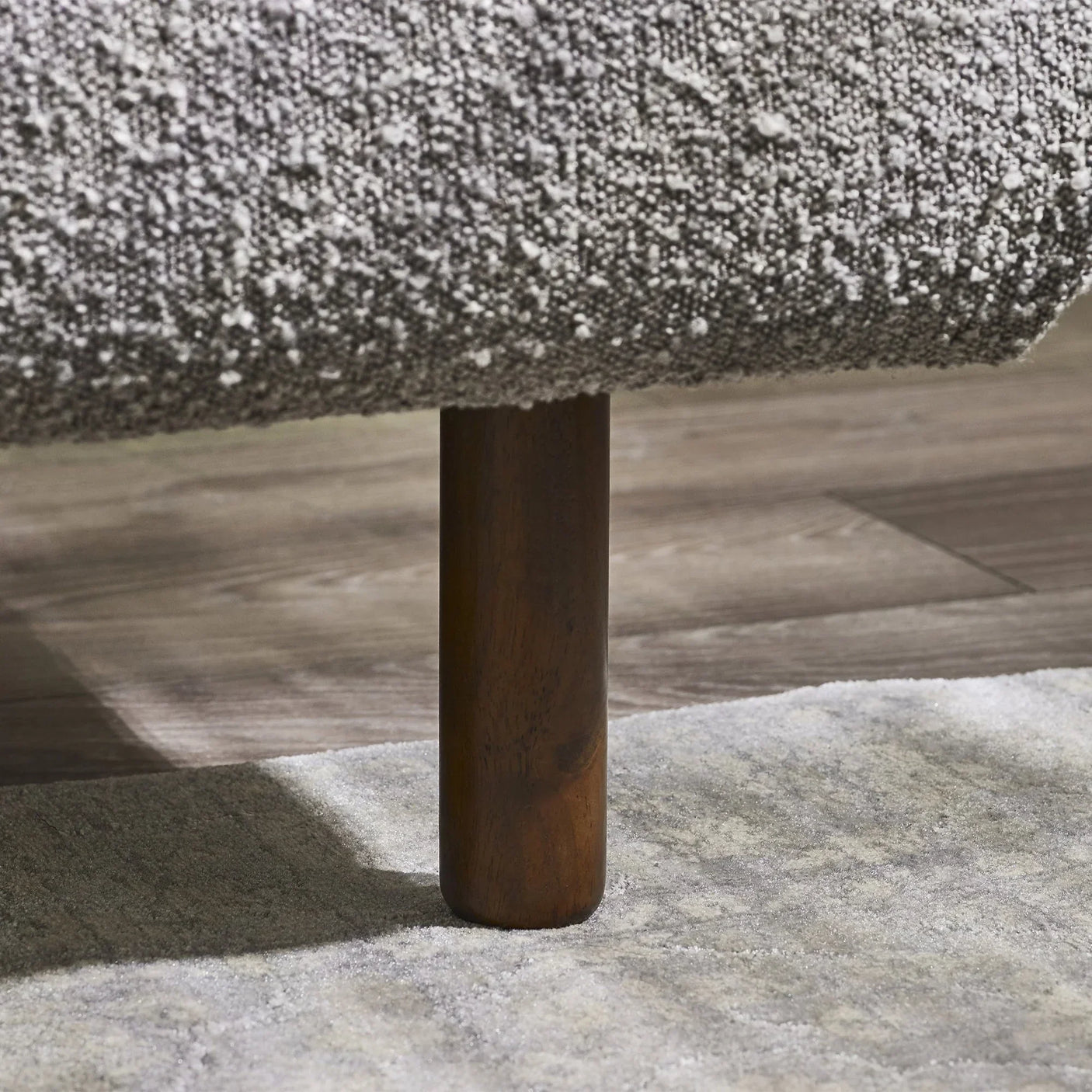 Hannah bed wooden leg detail with textured grey fabric upholstery on wooden floor