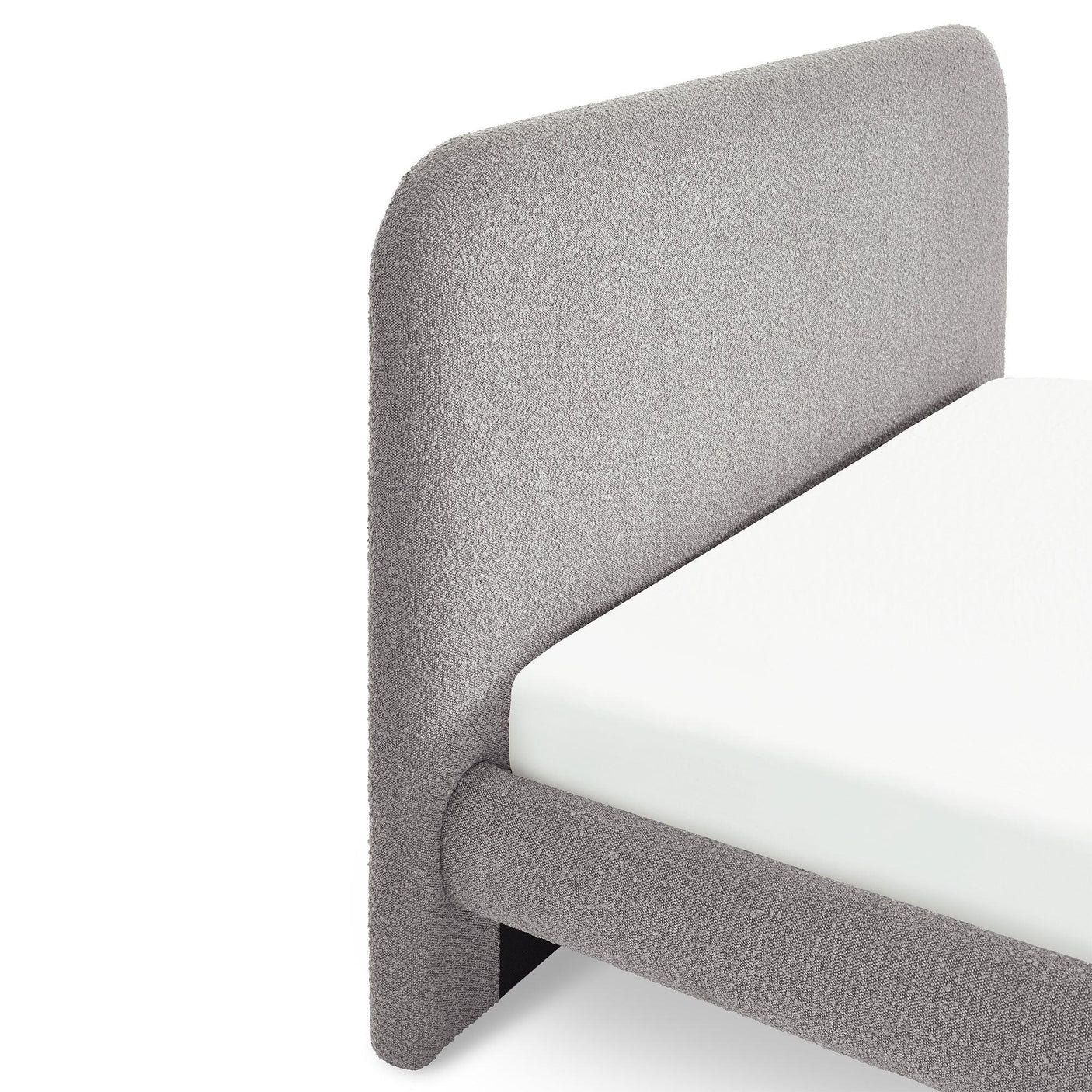 Grey upholstered bed frame with curved headboard and white mattress, close up view