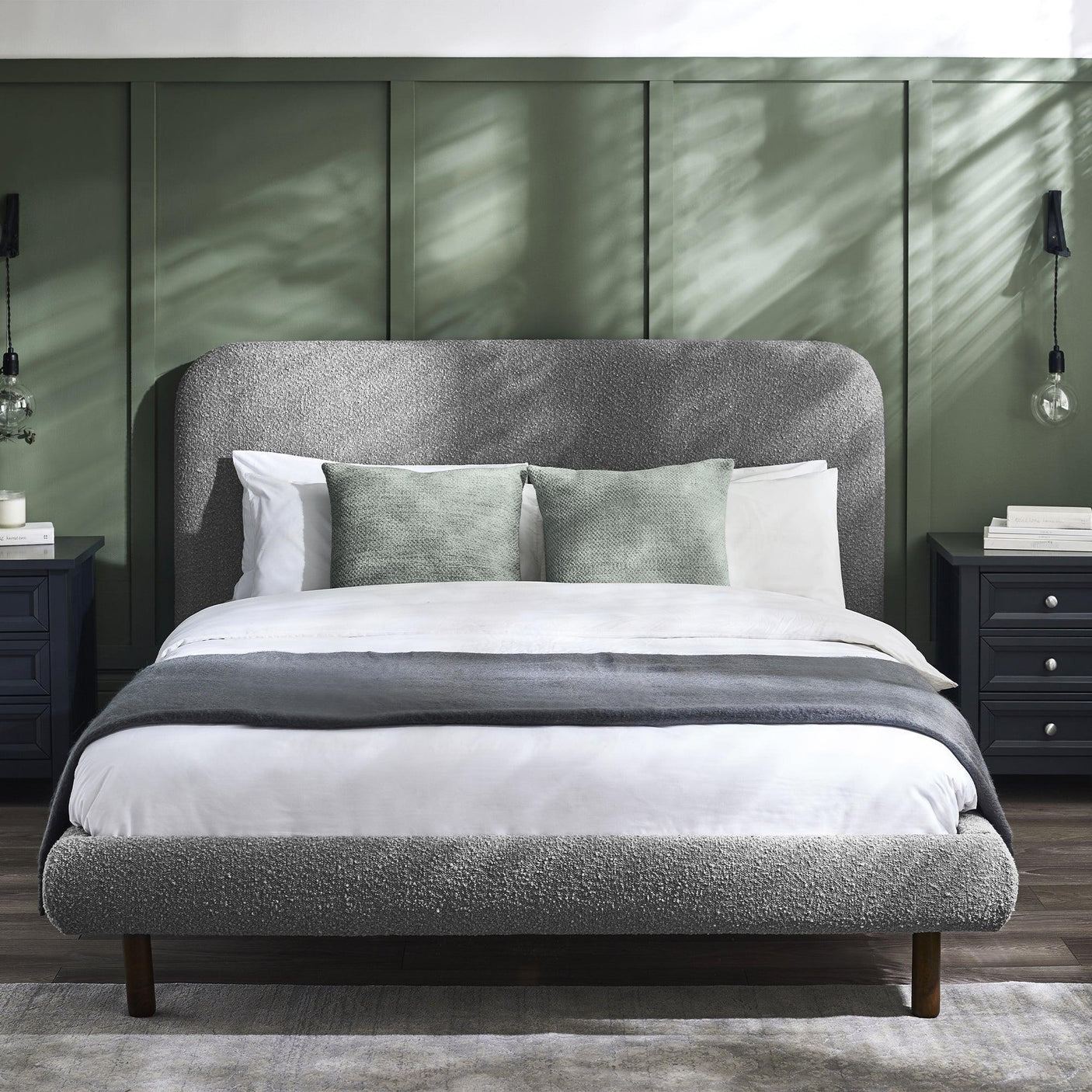 Grey upholstered Hannah bed 135cm with green cushions, beside navy bedside tables