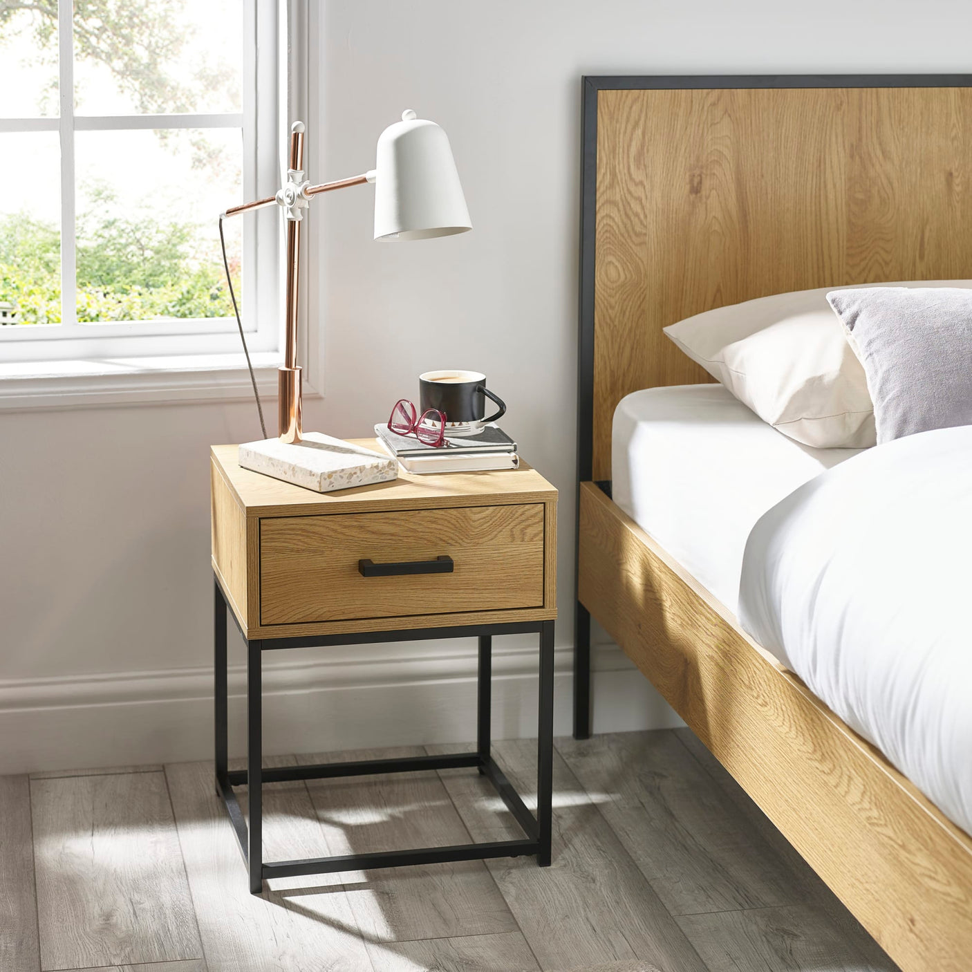 Oak bedside table with black metal frame and drawer beside modern bed
