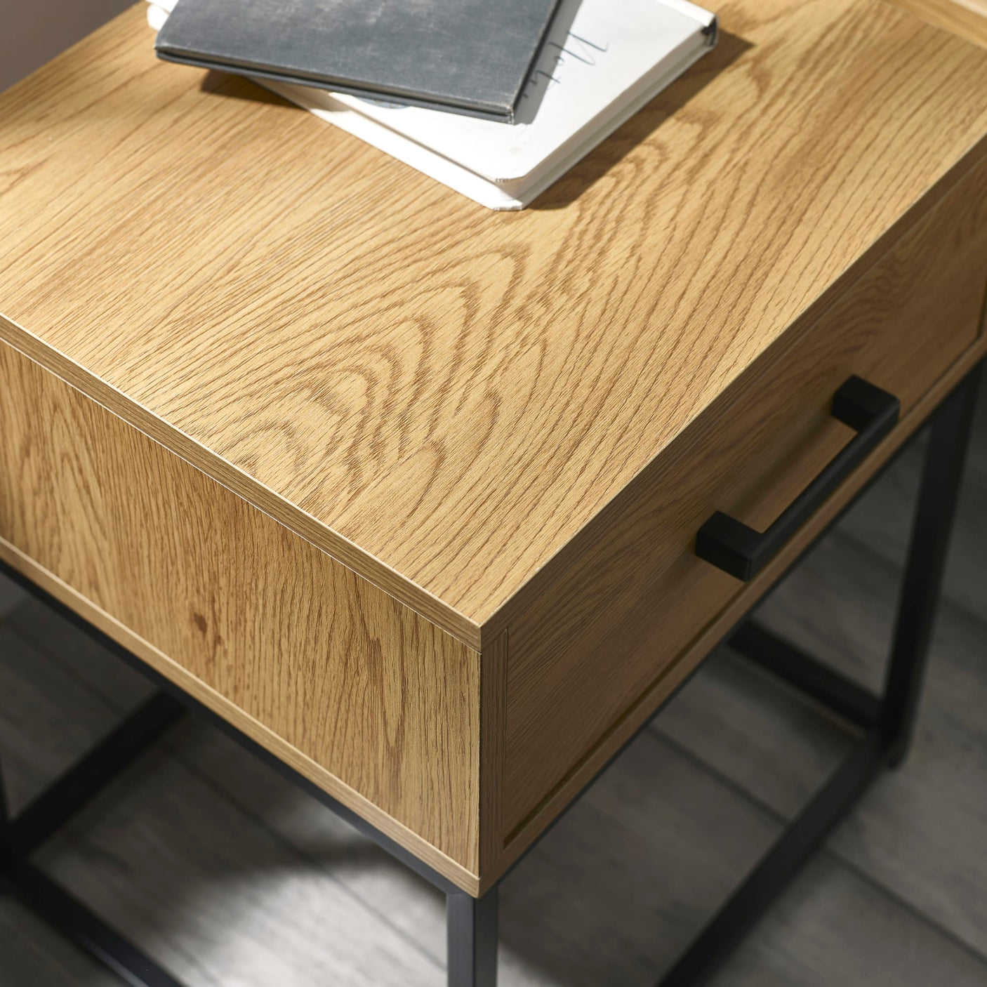 Oak wood desk with black metal legs and handle, close up on drawer corner