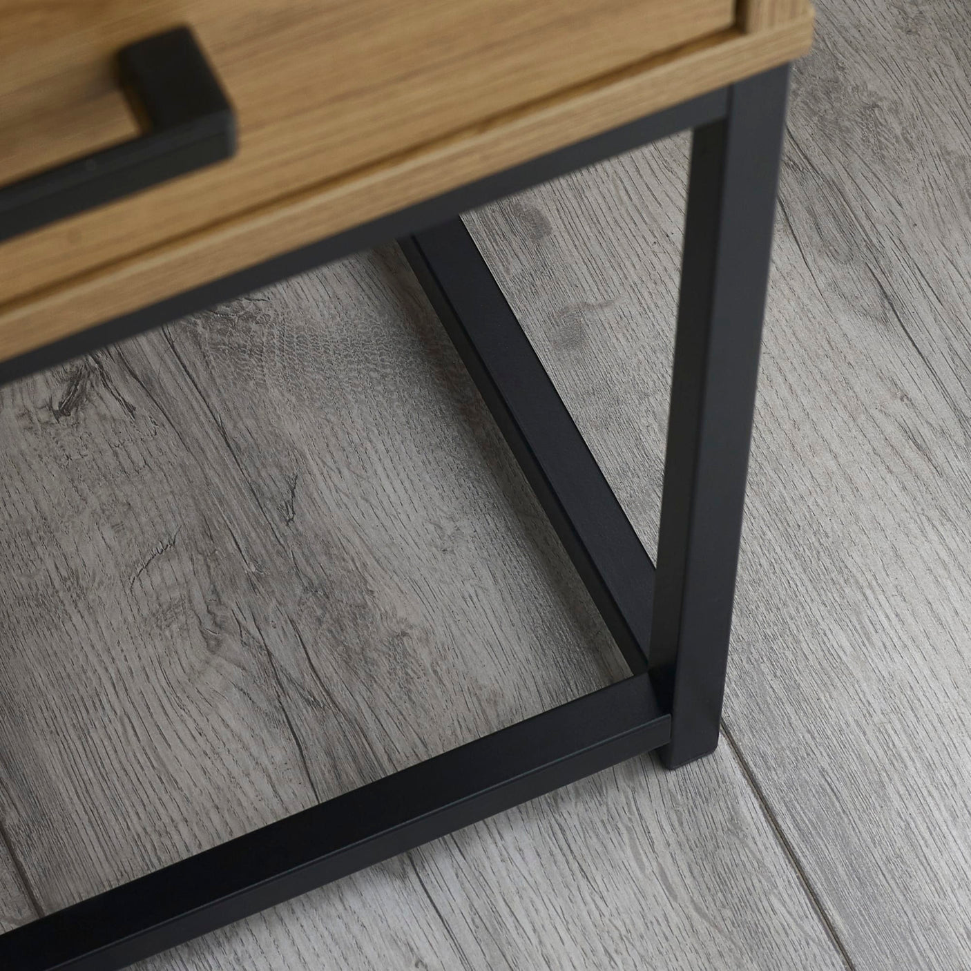 Black metal table leg with oak wood detail on light grey wood floor