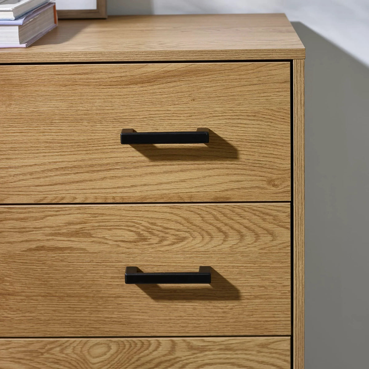 Oak wood chest of drawers with black metal handles, close-up of top drawers