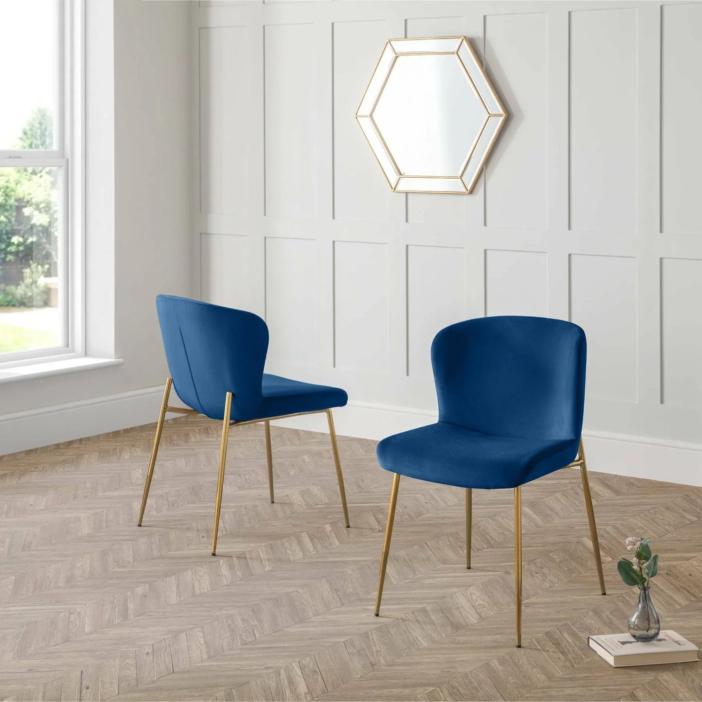 Blue accent chairs with gold legs in modern room with panelled walls and hexagon mirror