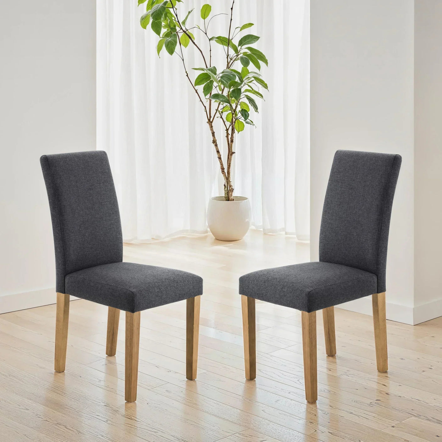 Pair of grey fabric dining chairs with wooden legs on light wood floor