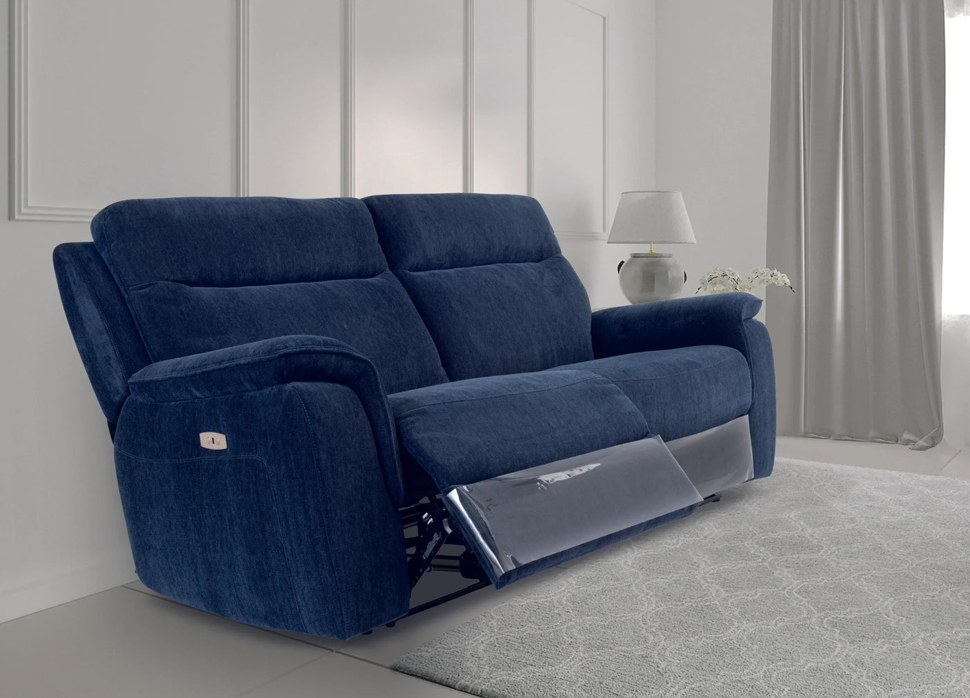 Blue fabric recliner sofa with footrest extended in bright living room with lamp and curtains