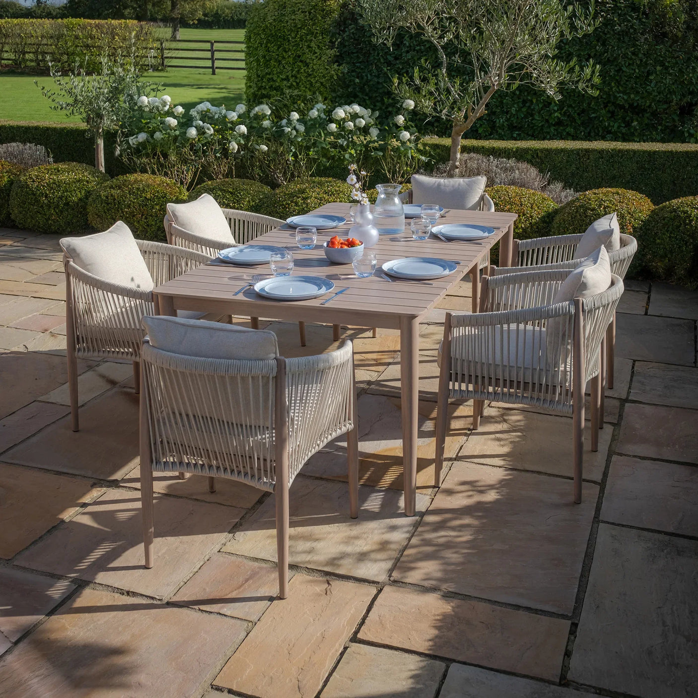 6 seat outdoor dining set with rope chairs and wooden table on stone patio
