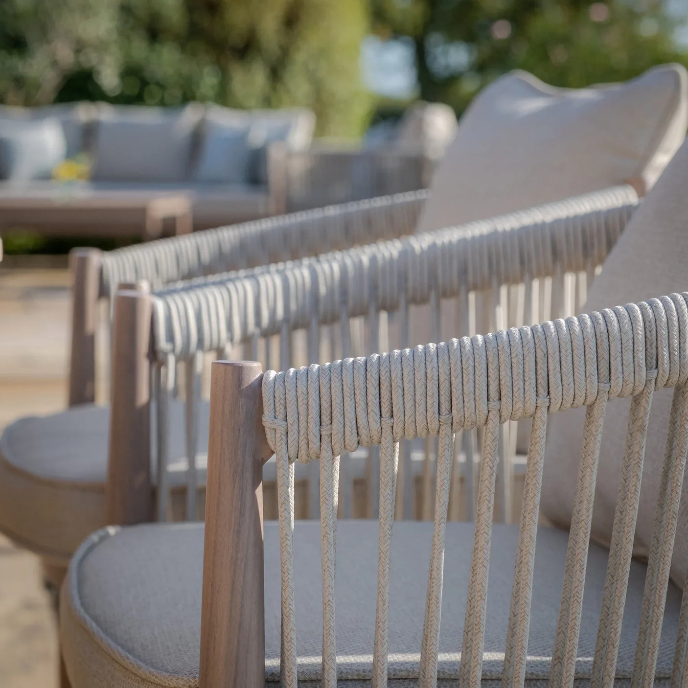 Close view of rope weave outdoor dining chairs with taupe cushions on patio