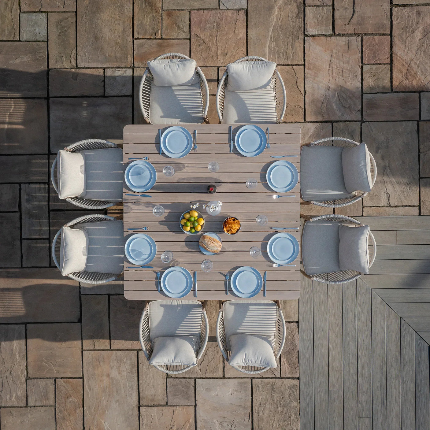 Outdoor dining set with eight cushioned chairs and a square wooden table set for a meal