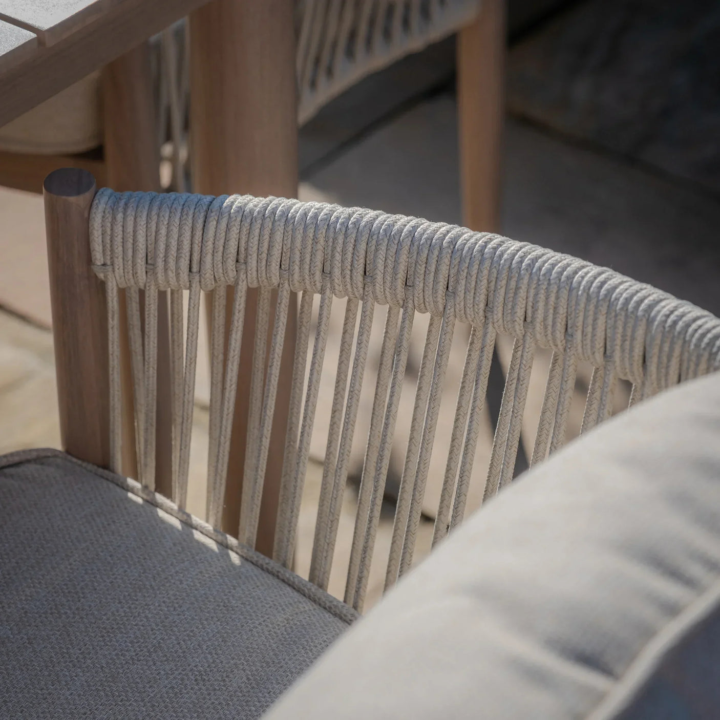 Close up of outdoor rope dining chair with taupe cushion and wooden frame