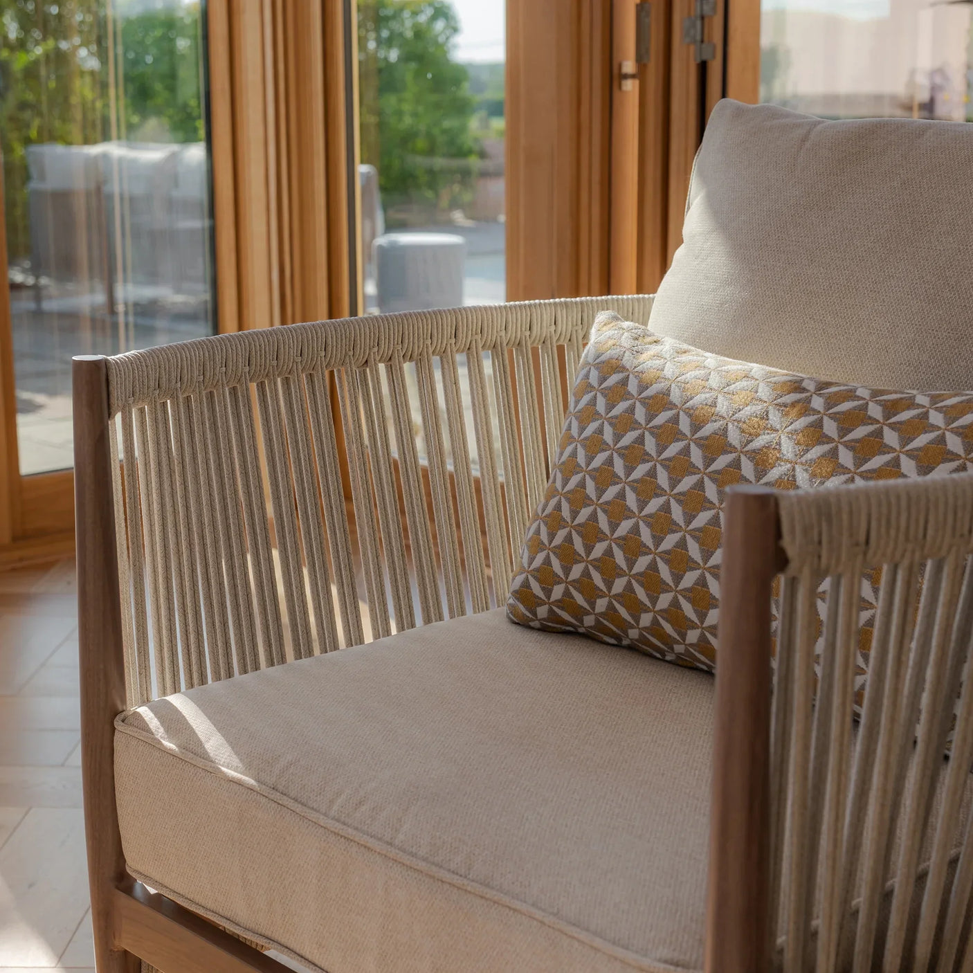 Beige rope accent armchair with textured seat cushion and geometric patterned pillow