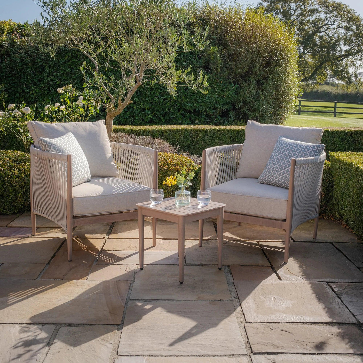 Outdoor garden furniture set with two cushioned armchairs and coffee table on patio