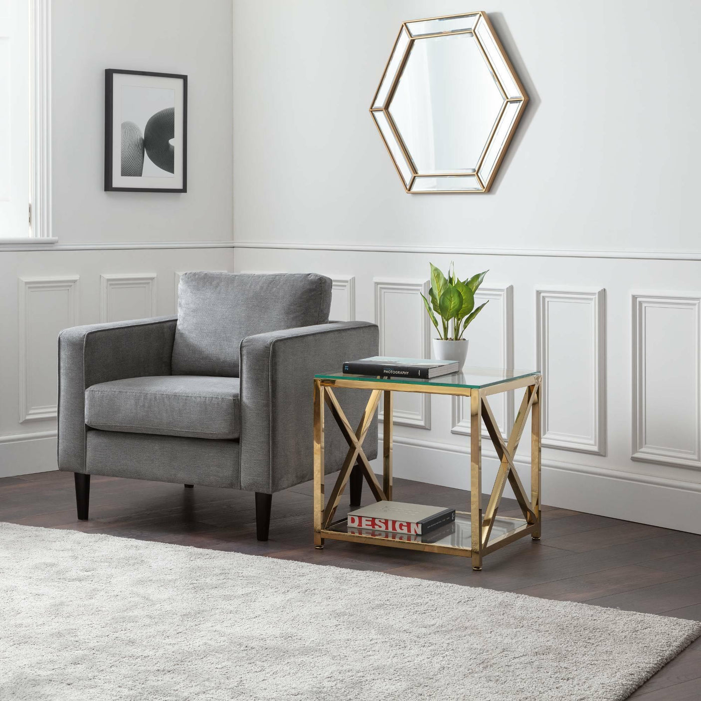 Dark grey chenille armchair in modern living room with gold glass side table and wall decor