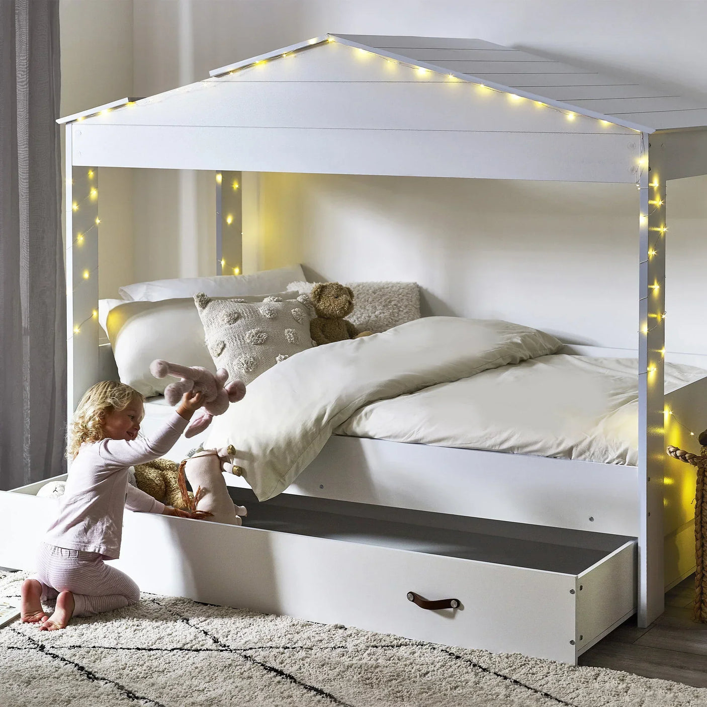 White kids low sleeper bed with fairy lights and pull-out storage drawer in bedroom