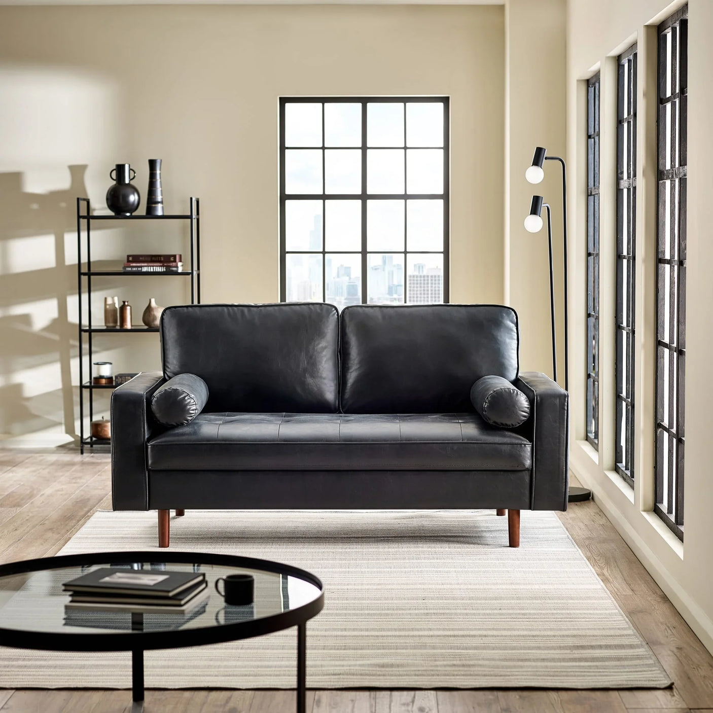 Black leather sofa with cylindrical arm cushions in modern living room setting