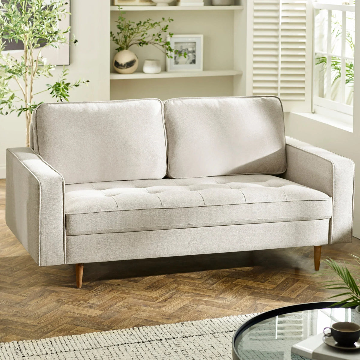 Light beige fabric sofa with tufted seat and wooden legs in modern living room setting