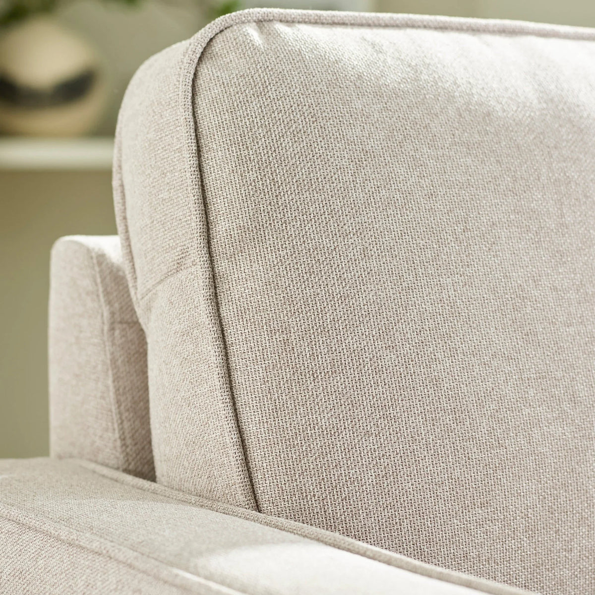 Close-up of beige fabric sofa backrest and armrest with textured upholstery