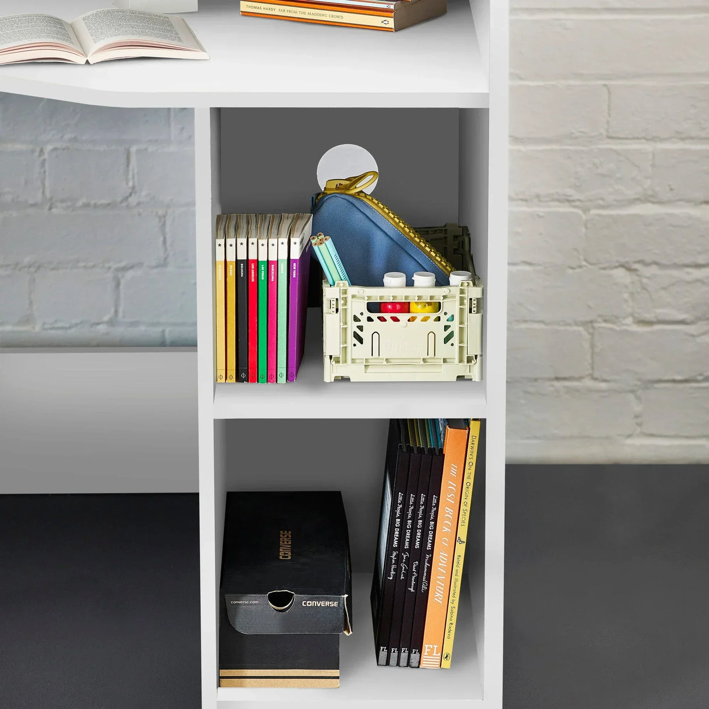 White bookcase shelves with books, storage box, pencil case, and Converse shoe box