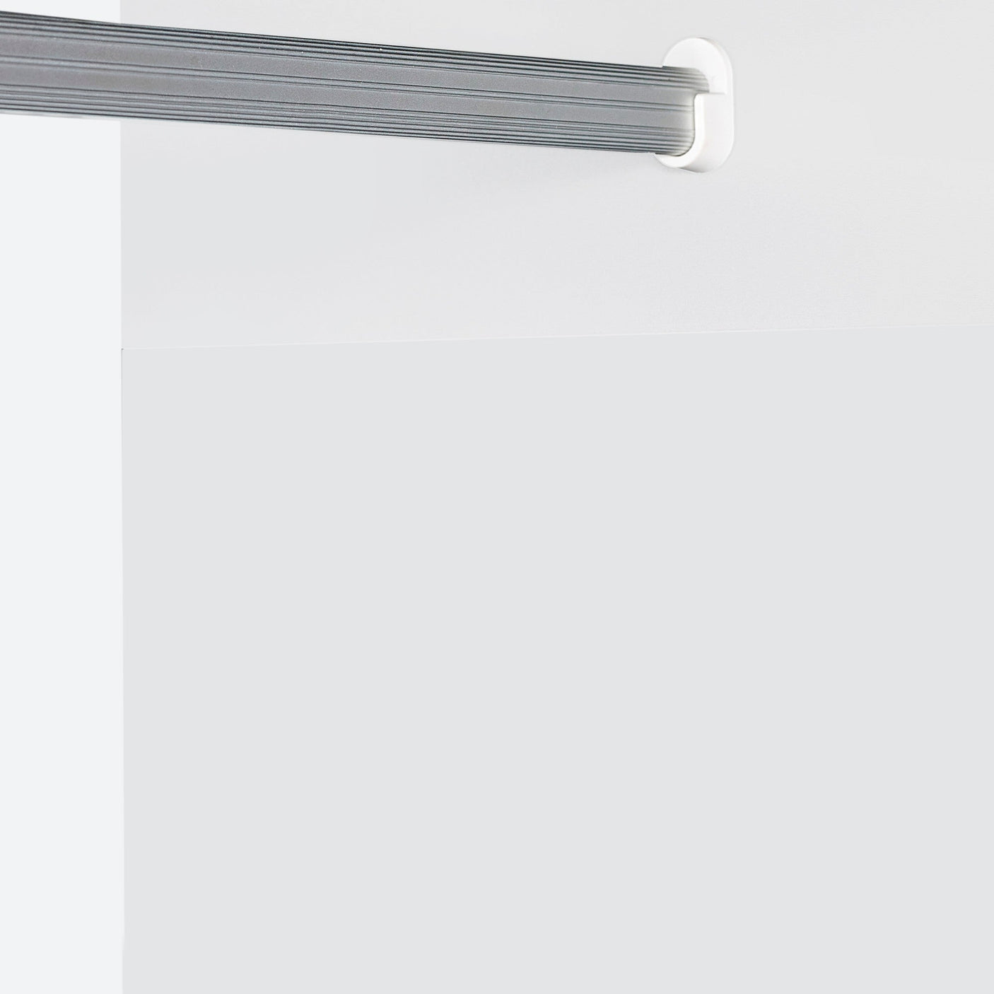 Grey wardrobe rail with white wall mounts fitted inside wardrobe interior