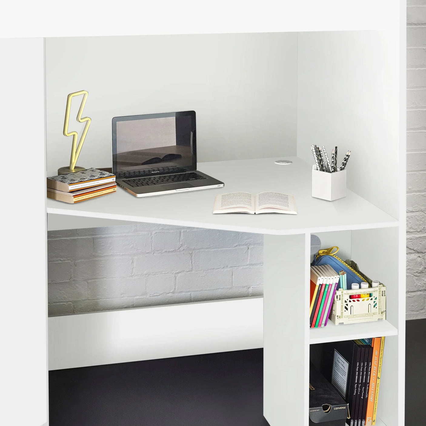 White corner desk with laptop, books, pen holder and lower shelves for office storage